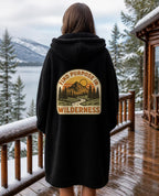 Find Purpose in the Wilderness Hooded Sherpa Blanket in Black worn by a woman, back view on a snowy porch – digital mockup