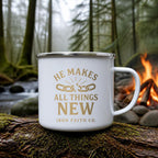 He Makes All Things New Enamel Camp Mug (white enamel) on a mossy log beside a campfire – digital mockup