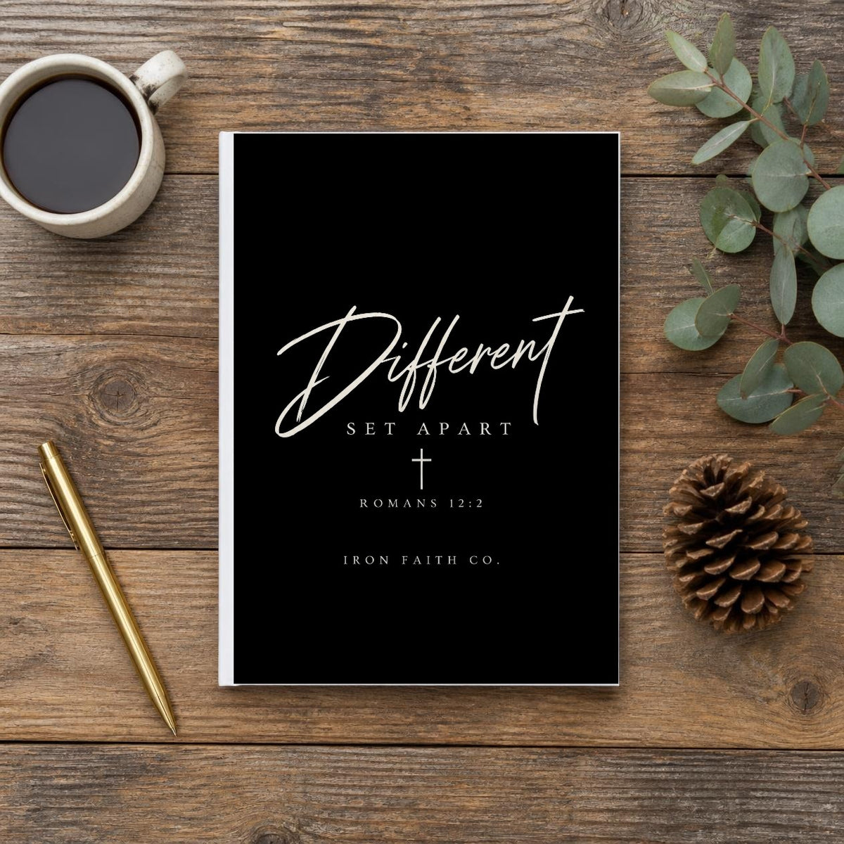 The Different Romans 12:2 Hardcover Journal on a wooden table with coffee, a pen and a pine cone (digitally composited scene image)