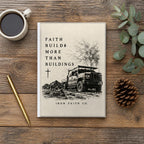 The Faith Builds More Than Buildings Hardcover Journal on a wooden table with coffee, a pen and a pine cone (digitally composited scene image)