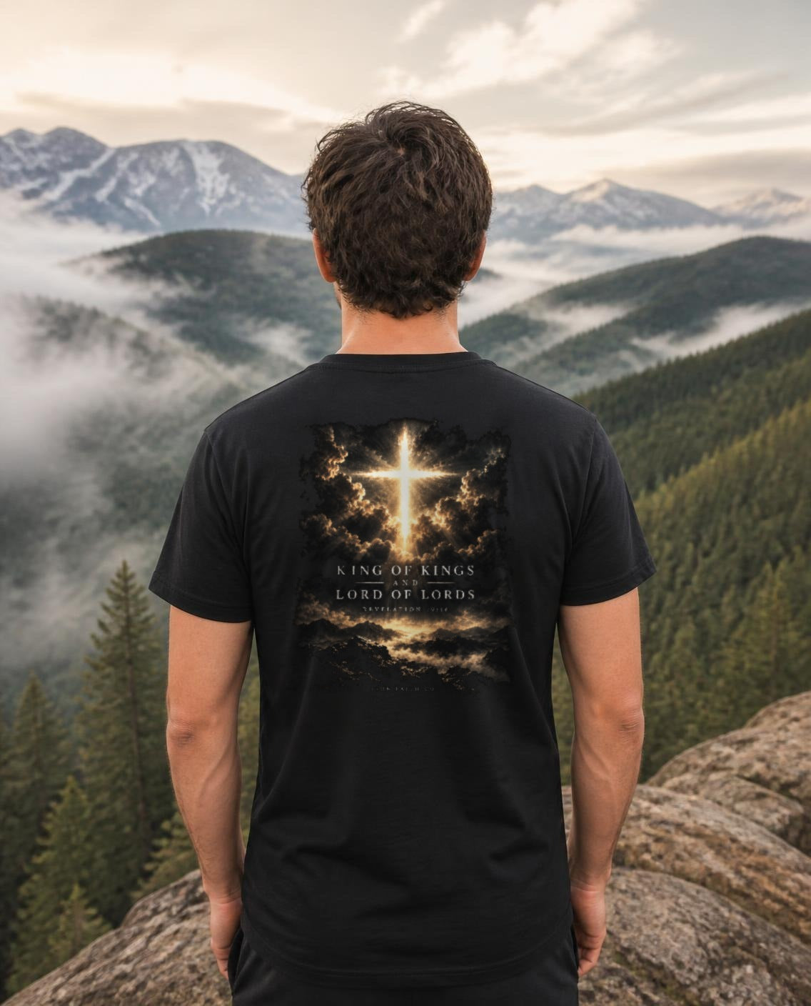 Fictional model wearing the King of Kings Revelation 19:16 Tee – Back Print in Black, back view, Pacific Northwest scene (digitally composited lifestyle image)