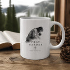The Pray Harder Mug (11oz, white) on a wooden cabin table with an open Bible and pine cones (digitally composited scene image)