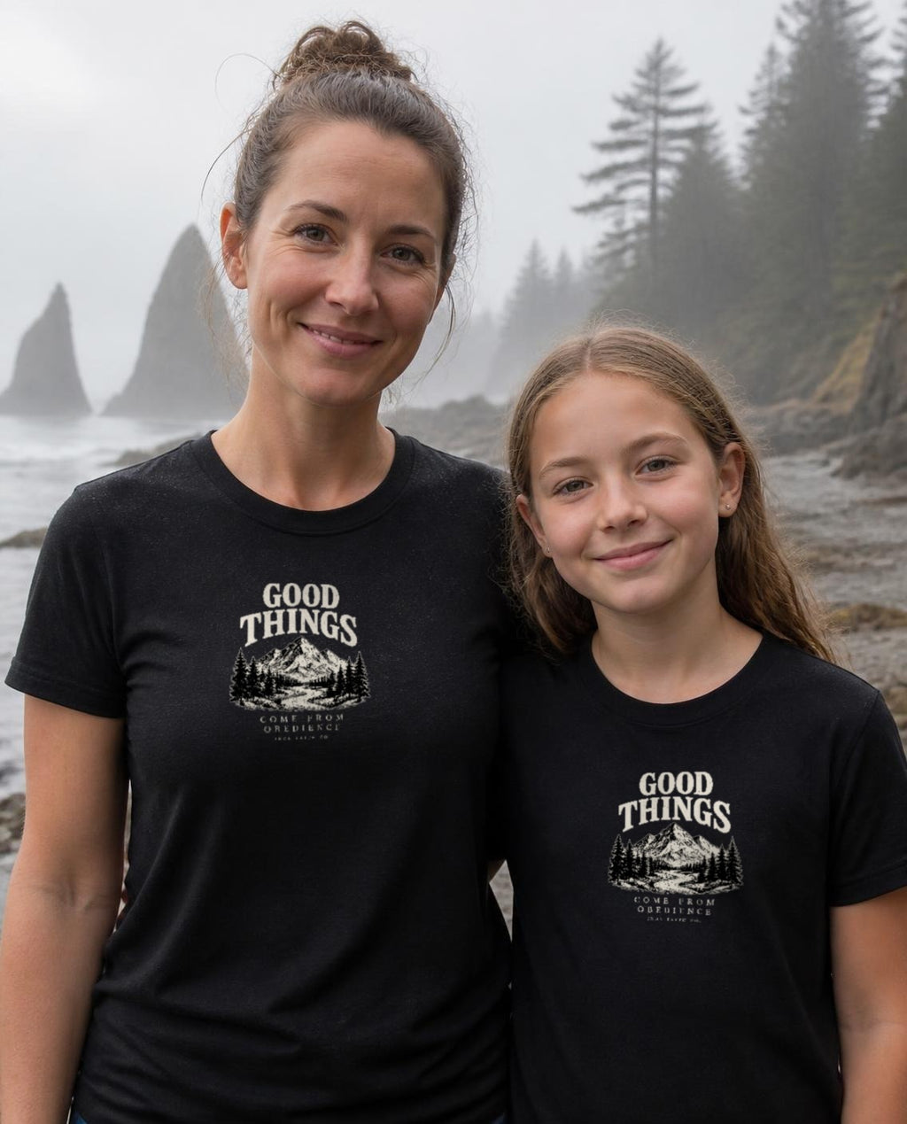 Lifestyle image (digitally composited, real print artwork at true print size): Good Things Come From Obedience tee on a fictional mother and daughter (women's and youth sizes) on a misty Pacific Northwest beach