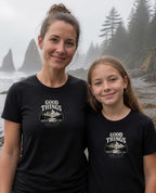 Lifestyle image (digitally composited, real print artwork at true print size): Good Things Come From Obedience tee on a fictional mother and daughter (women's and youth sizes) on a misty Pacific Northwest beach