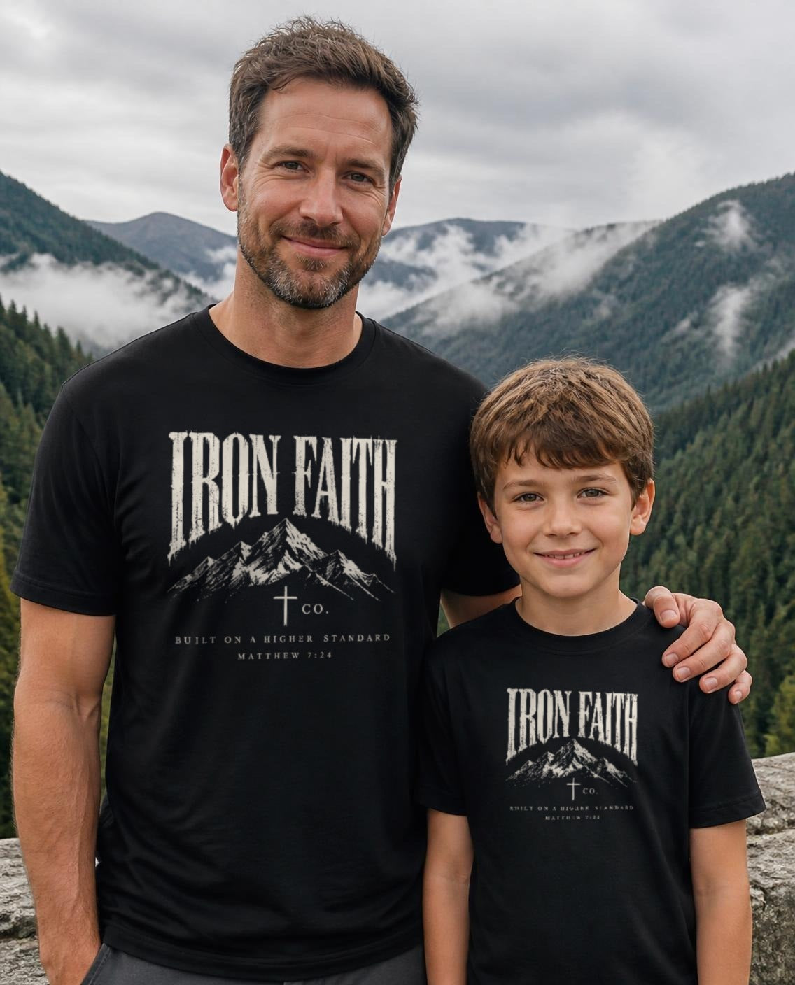 Lifestyle image (digitally composited, real print artwork at true print size): Built on a Higher Standard tee on a fictional father and son (adult and youth sizes) at a misty mountain overlook