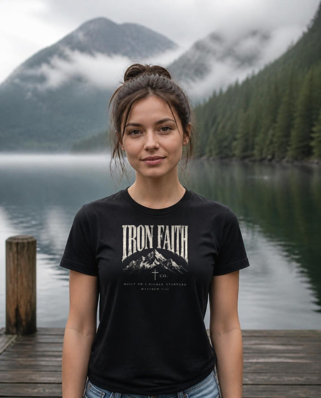 Fictional model wearing the Built on a Higher Standard Women's Fitted Tee in Black, Pacific Northwest scene (digitally composited lifestyle image)