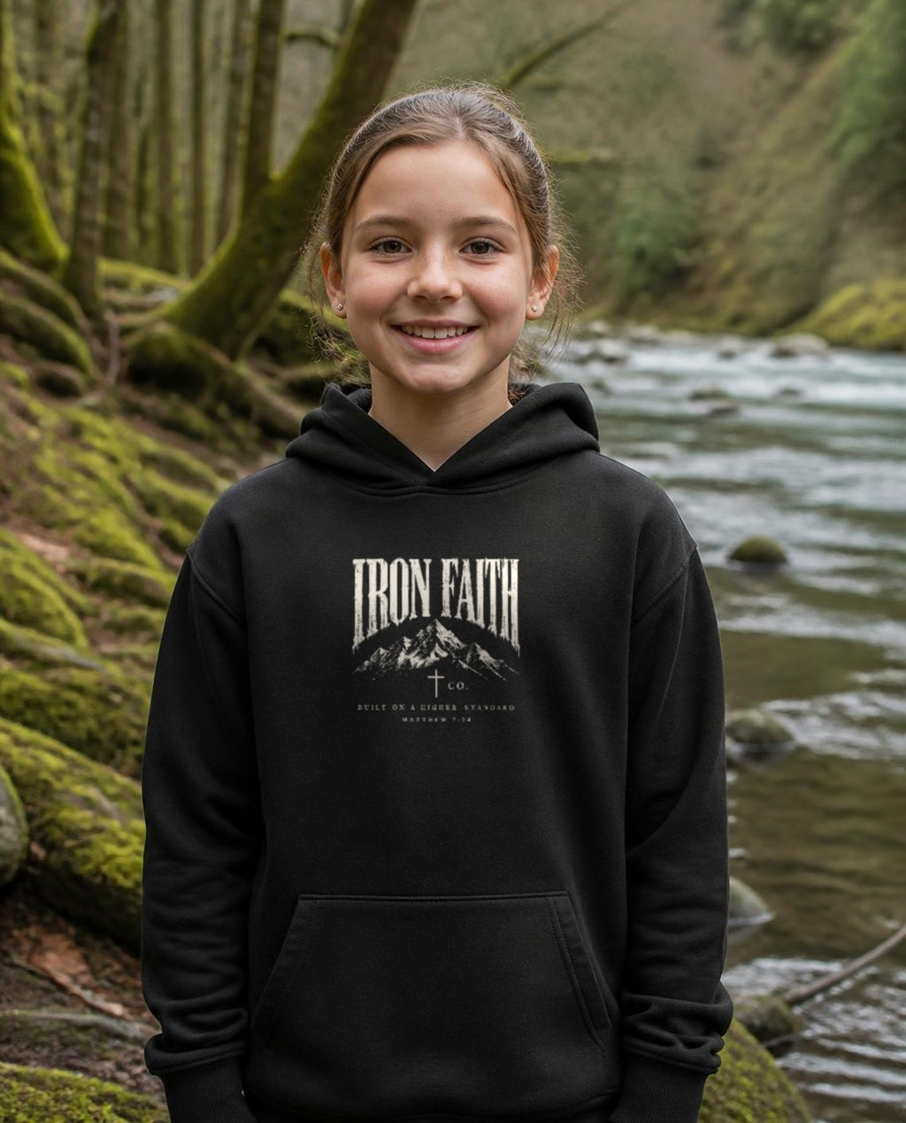 Fictional model wearing the Built on a Higher Standard Youth Hoodie in Black, Pacific Northwest scene (digitally composited lifestyle image)