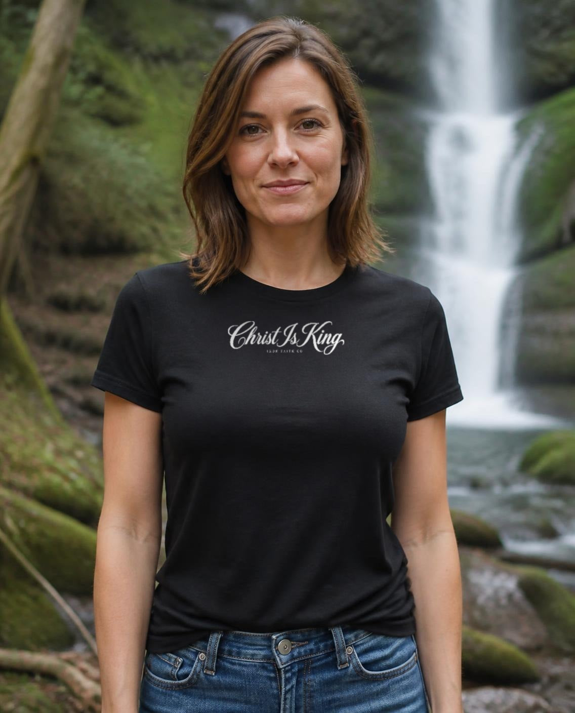 Fictional model wearing the Christ Is King Women's Fitted Tee in Black, Pacific Northwest scene (digitally composited lifestyle image)