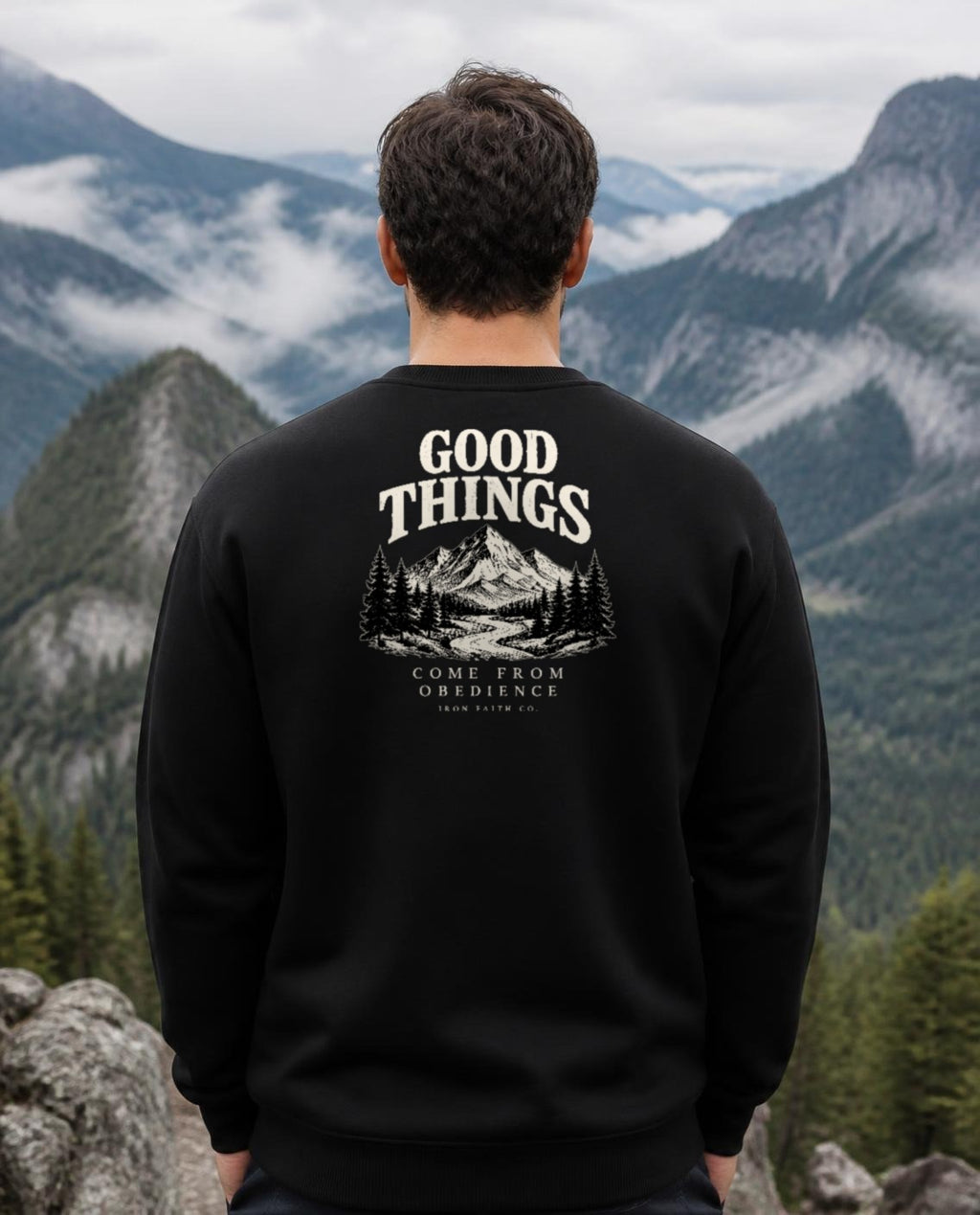 Fictional model wearing the Good Things Come From Obedience Crewneck – Back Print in Black, back view, Pacific Northwest scene (digitally composited lifestyle image)