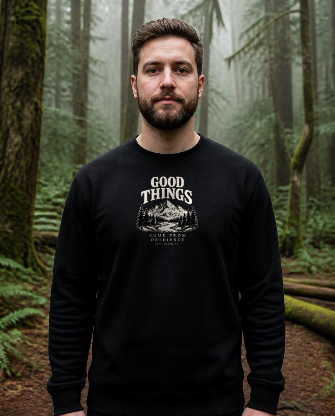 Fictional model wearing the Good Things Come From Obedience Crewneck in Black, Pacific Northwest scene (digitally composited lifestyle image)