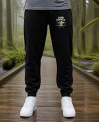Fictional model wearing the Good Things Come From Obedience Sweatpants in Black, Pacific Northwest scene (digitally composited lifestyle image)