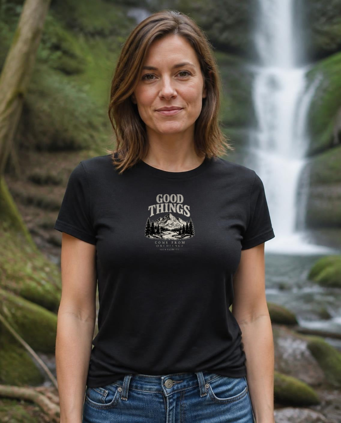 Fictional model wearing the Good Things Come From Obedience Women's Fitted Tee in Black, Pacific Northwest scene (digitally composited lifestyle image)