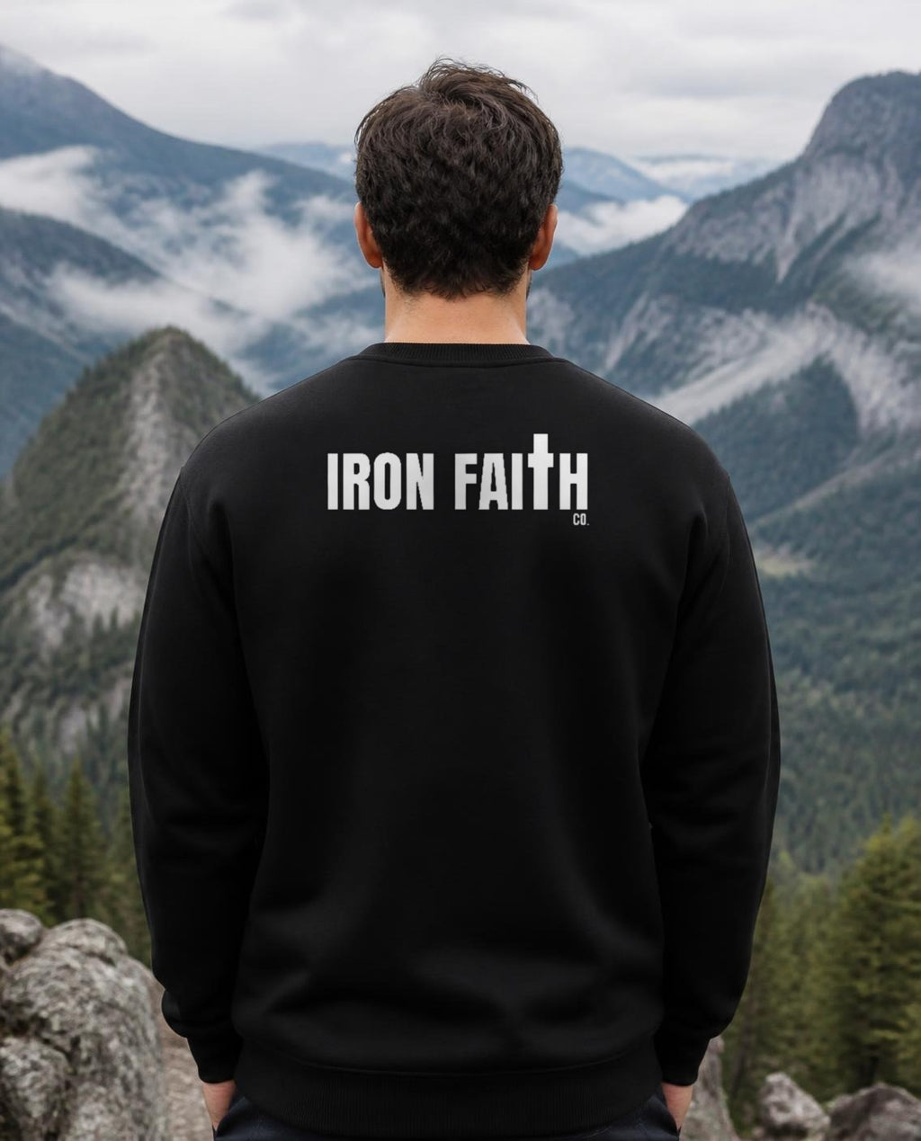 Fictional model wearing the Iron Faith Co. Wordmark Crewneck – Back Print in Black, back view, Pacific Northwest scene (digitally composited lifestyle image)