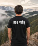 Fictional model wearing the Iron Faith Co. Wordmark Tee – Back Print in Black, back view, Pacific Northwest scene (digitally composited lifestyle image)