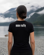 Fictional model wearing the Iron Faith Co. Wordmark Women's Fitted Tee – Back Print in Black, back view, Pacific Northwest scene (digitally composited lifestyle image)