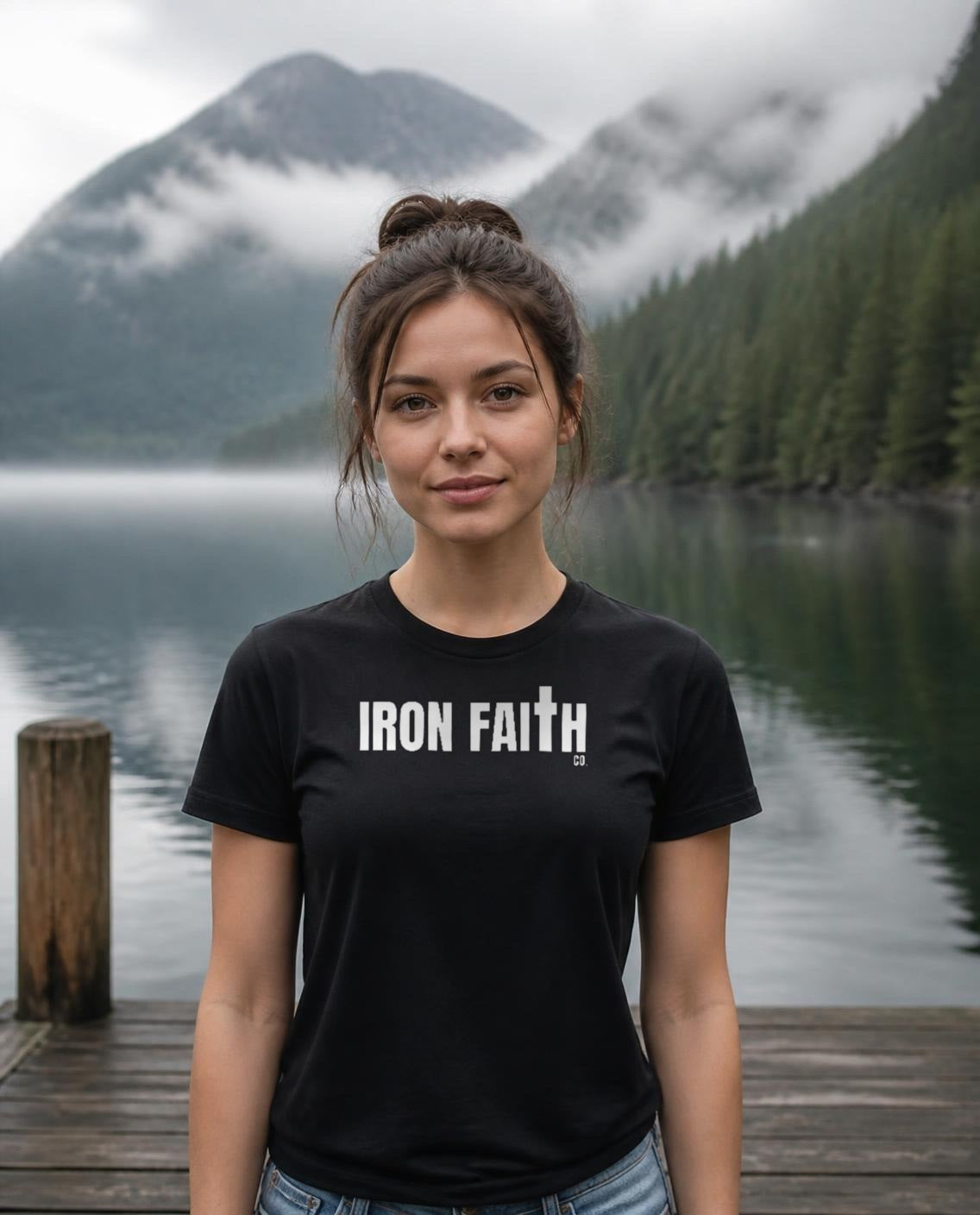 Fictional model wearing the Iron Faith Co. Wordmark Women's Fitted Tee in Black, Pacific Northwest scene (digitally composited lifestyle image)