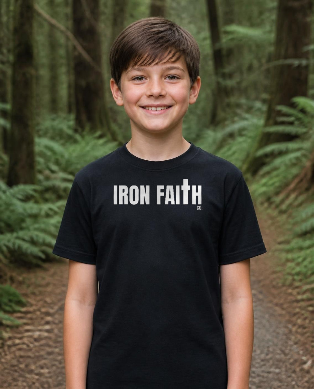 Fictional model wearing the Iron Faith Co. Wordmark Youth Tee in Black, Pacific Northwest scene (digitally composited lifestyle image)