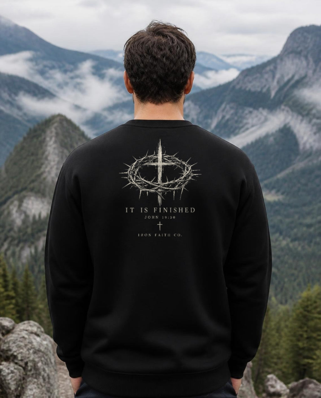Fictional model wearing the It Is Finished Crewneck in Black, back view, Pacific Northwest scene (digitally composited lifestyle image)