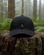 It Is Finished Dad Hat in Black shown outdoors (digitally composited lifestyle image)
