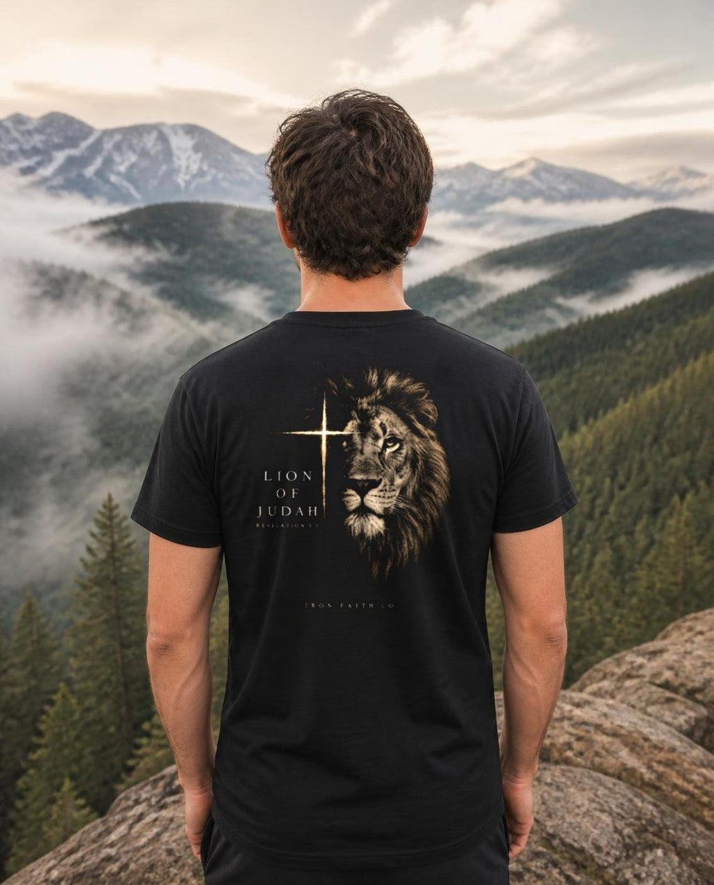 Fictional model wearing the Lion of Judah Tee – Back Print in Black, back view, Pacific Northwest scene (digitally composited lifestyle image)