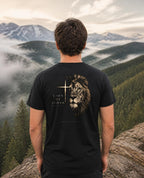 Fictional model wearing the Lion of Judah Tee – Back Print in Black, back view, Pacific Northwest scene (digitally composited lifestyle image)