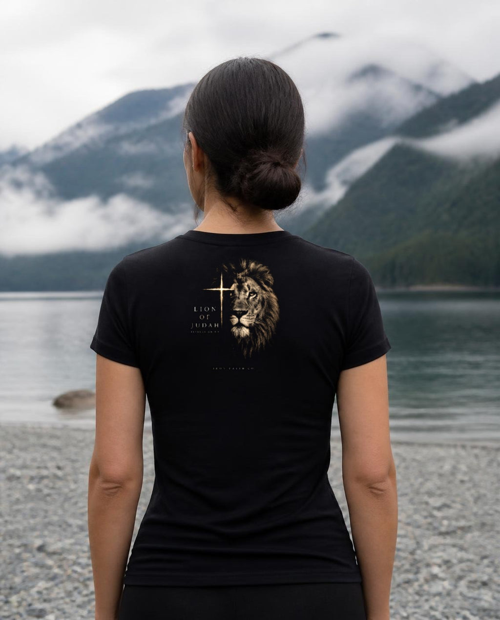 Fictional model wearing the Lion of Judah Women's Fitted Tee – Back Print in Black, back view, Pacific Northwest scene (digitally composited lifestyle image)