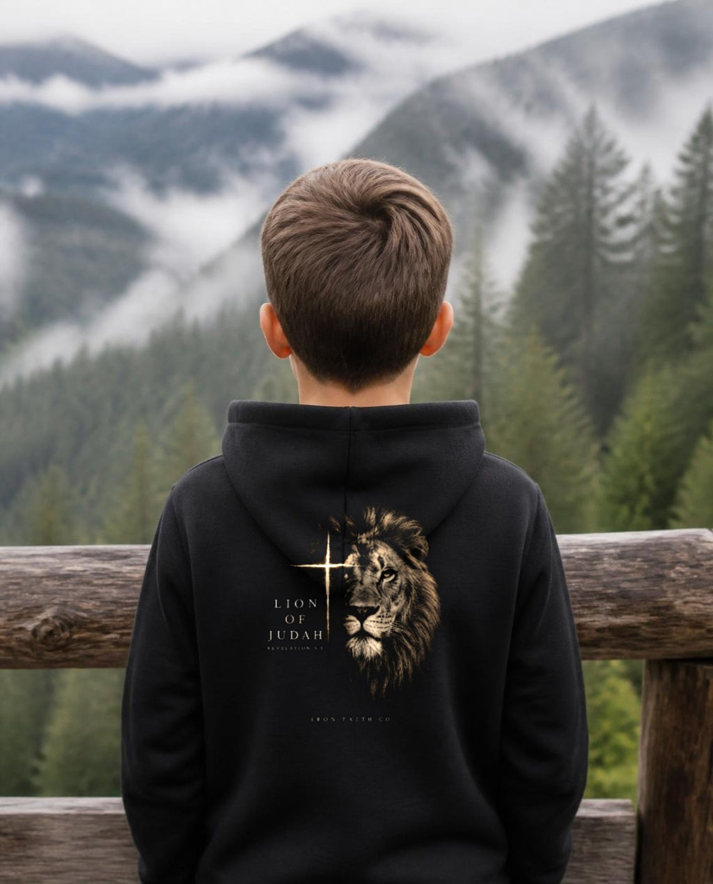 Fictional model wearing the Lion of Judah Youth Hoodie – Back Print in Black, back view, Pacific Northwest scene (digitally composited lifestyle image)