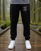 Fictional model wearing the Walk By Faith Sweatpants in Black, Pacific Northwest scene (digitally composited lifestyle image)