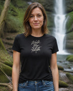 Fictional model wearing the Walk By Faith Women's Fitted Tee in Black, Pacific Northwest scene (digitally composited lifestyle image)